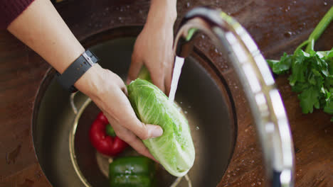 Hands-of-caucasian-pregnant-woman-washing-vegetables-in-kitchen