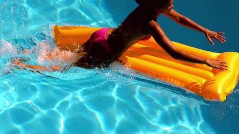 Woman-in-pink-bikini-jumping-into-swimming-pool-onto-lilo