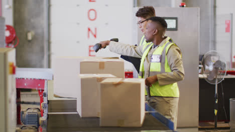 Diverse-male-workers-wearing-safety-suits-and-scanning-boxes-in-warehouse