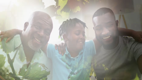 Composite-of-happy-african-american-son,-father-and-grandfather-embracing,-with-sunlight-and-nature