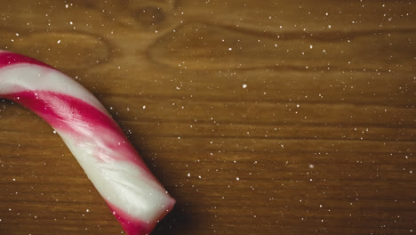 Snow-falling-over-close-up-of-candy-can-on-wooden-surface
