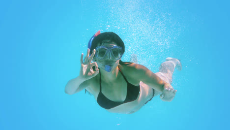 Morena-Nadando-Bajo-El-Agua-Usando-Snorkel-Haciendo-La-Señal-De-Ok