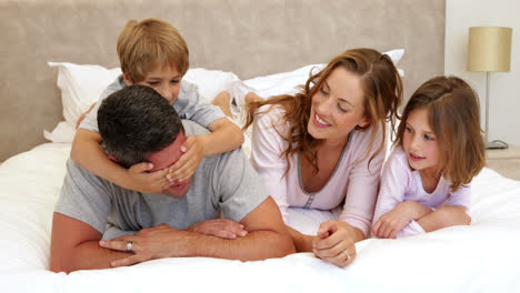 Cute-parents-and-children-lying-on-bed-joking