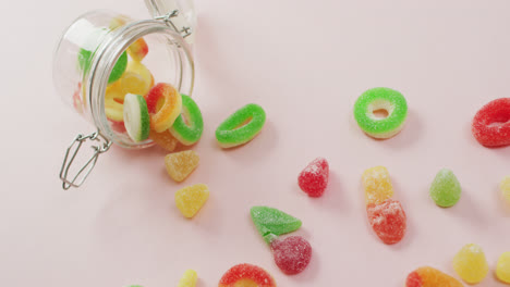 Video-of-colourful-jelly-candy-and-jar-on-pink-background