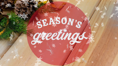 Animation-of-season's-greetings-text-over-christmas-decoration-on-table