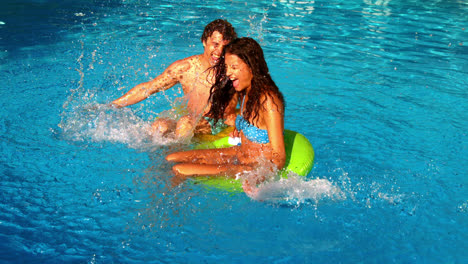 Young-couple-splashing-and-having-fun-in-swimming-pool