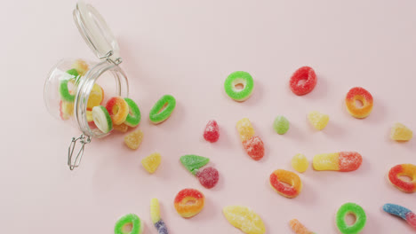 Video-of-colourful-jelly-candy-and-jar-on-pink-background
