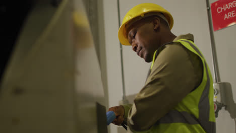 African-american-male-worker-wearing-safety-suit-with-helmet-in-warehouse