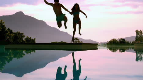 Couple-jumping-into-swimming-pool-holding-hands