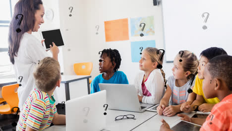 Animation-of-question-marks-over-female-elementary-school-teacher-and-diverse-pupils-with-computers