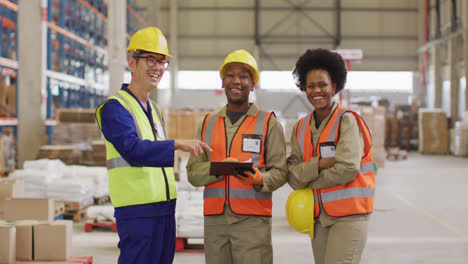 Portrait-of-diverse-workers-wearing-safety-suits-and-smiling-in-warehouse