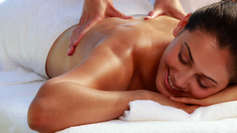 Happy-brunette-enjoying-a-massage-poolside