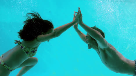 Glückliches-Paar-Hand-In-Hand-Unter-Wasser-Im-Schwimmbad