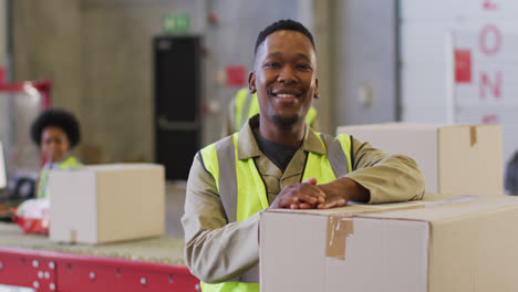 Portrait-of-african-american-male-worker-wearing-safety-suit-and-smiling-in-warehouse