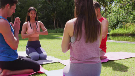 Happy-diverse-group-practicing-yoga-pose-kneeling-on-mats-in-sunny-park