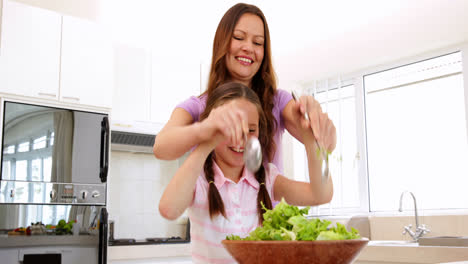 Mother-showing-her-daughter-how-to-toss-a-salad