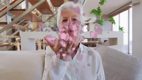 Animation-of-pink-hearts-over-happy-caucasian-senior-woman-making-video-call-at-home