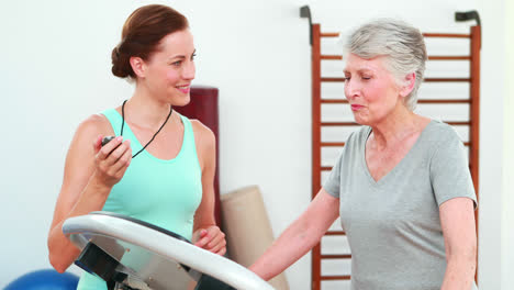 Trainer-watching-elderly-client-using-treadmill