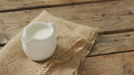 Video-of-glass-jug-of-milk-on-wooden-background