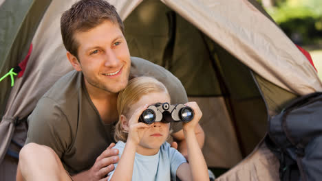 Smiling-caucasian-father-and-child-in-tent,-child-birdwatching-with-binoculars