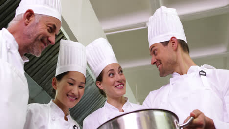 Chef-showing-colleagues-contents-of-large-pot-low-angle-view