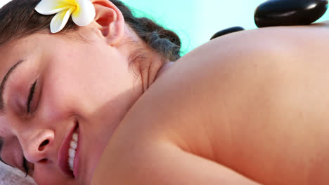 Brunette-enjoying-a-hot-stone-massage-poolside