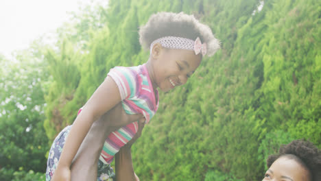 Glückliches-Afroamerikanisches-Paar-Mit-Ihrer-Tochter,-Die-Im-Garten-Spielt