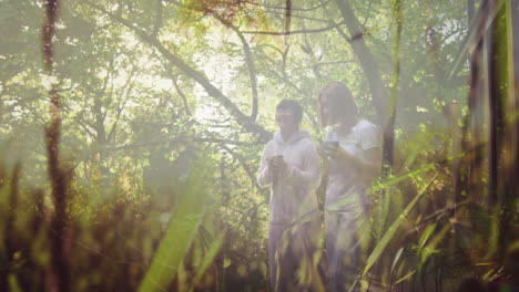 Composite-of-two-happy-asian-women-holding-tea-and-walking-forest,-and-moving-grass-and-nature
