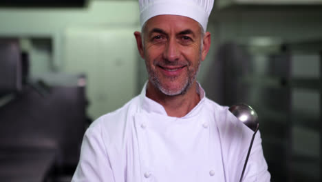 Head-chef-holding-a-ladle-smiling-at-camera