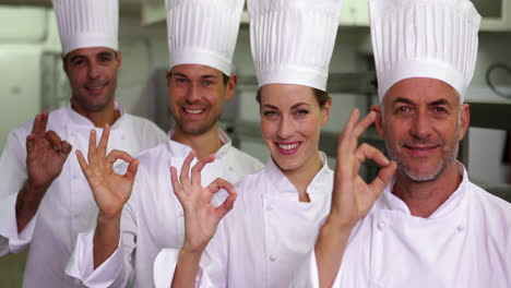 Four-cheerful-chefs-looking-at-camera-making-ok-sign