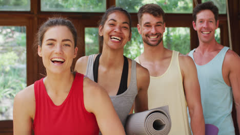 Portrait-of-happy,-diverse-group-of-men-and-women-laughing-after-yoga-class-in-studio