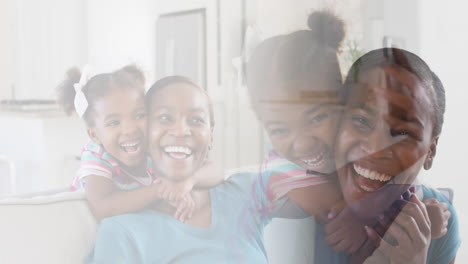 Composite-of-happy-african-american-mother-and-daughter-embracing-and-laughing-at-home