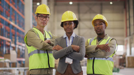 Portrait-of-diverse-workers-wearing-safety-suits-with-arms-crossed-in-warehouse