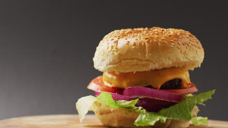 Video-of-cheeseburger-with-salad-in-burger-bun,-on-grey-background-with-copy-space
