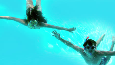 Happy-couple-wearing-snorkels-underwater-in-swimming-pool