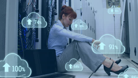 Animation-of-cloud-icons-with-growing-numbers-over-caucasian-woman-in-server-room