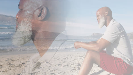 Composite-of-thoughtful-african-american-senior-man-sitting-on-beach-and-looking-out-to-sea