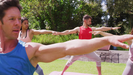 Grupo-Diverso-Practicando-Yoga-Con-Un-Instructor-Masculino-De-Pie-En-El-Parque-Soleado