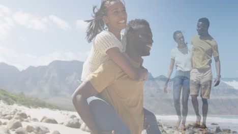 Composite-of-happy-african-american-couple-piggybacking,-and-embracing-walking-on-beach