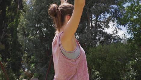 Smiling-caucasian-woman-with-arms-in-the-air-practicing-yoga-in-park