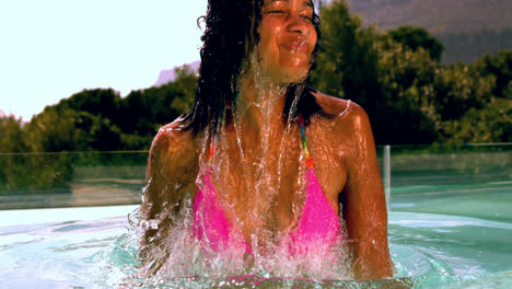 Happy-woman-in-pink-bikini-emerging-in-swimming-pool