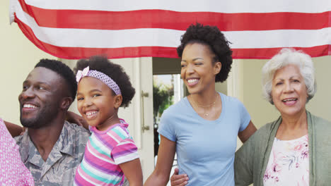 African-american-male-soldier-embracing-his-smiling-family-over-american-flag