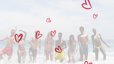 Animation-of-red-hearts-over-happy-diverse-group-of-friends-on-beach