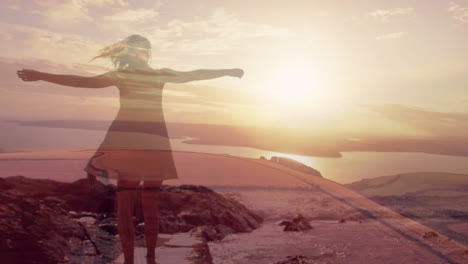 Composite-of-woman-dancing-with-outstretched-arms,and-sunset-sky-over-beach-and-sea