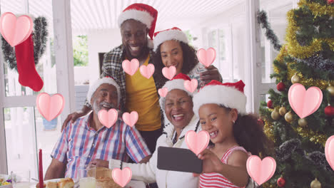 Animation-of-heart-icons-over-african-american-family-with-santa-hats