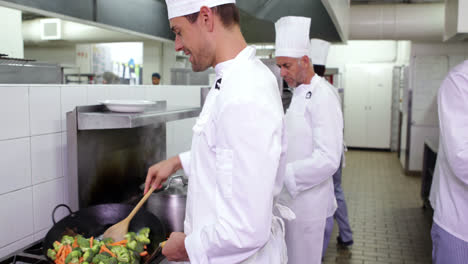 Smiling-chef-frying-vegetables-in-a-wok