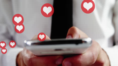 Animation-of-hearts-over-hands-of-biracial-man-using-smartphone
