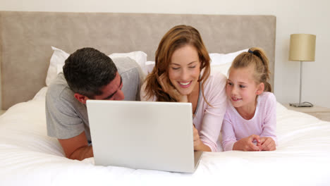 Family-using-laptop-together-on-bed