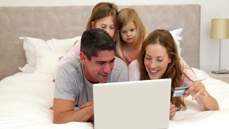 Eltern-Und-Töchter-Liegen-Im-Bett-Und-Kaufen-Mit-Dem-Laptop-Online-Ein