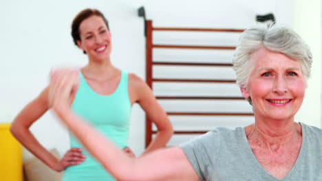 Trainer-watching-proud-elderly-client-flexing-her-bicep
